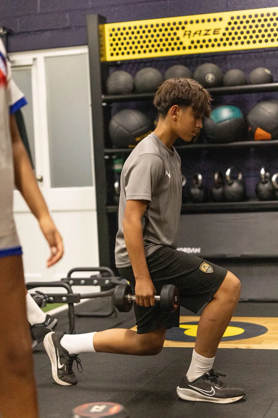 An athlete performing a dumbbell lunge in the gym