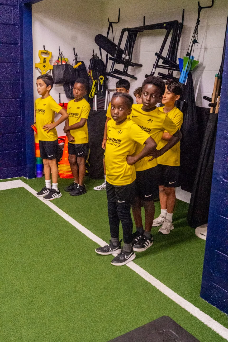 A group of junior athletes listening together on the indoor turf