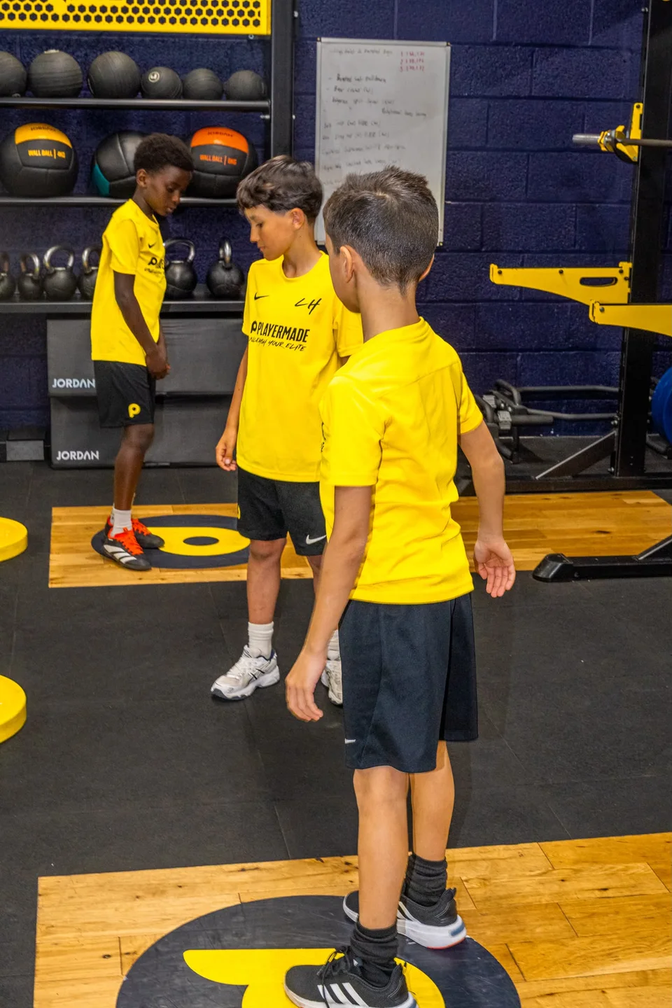 Junior athletes in yellow Playermade shirts during a group gym session