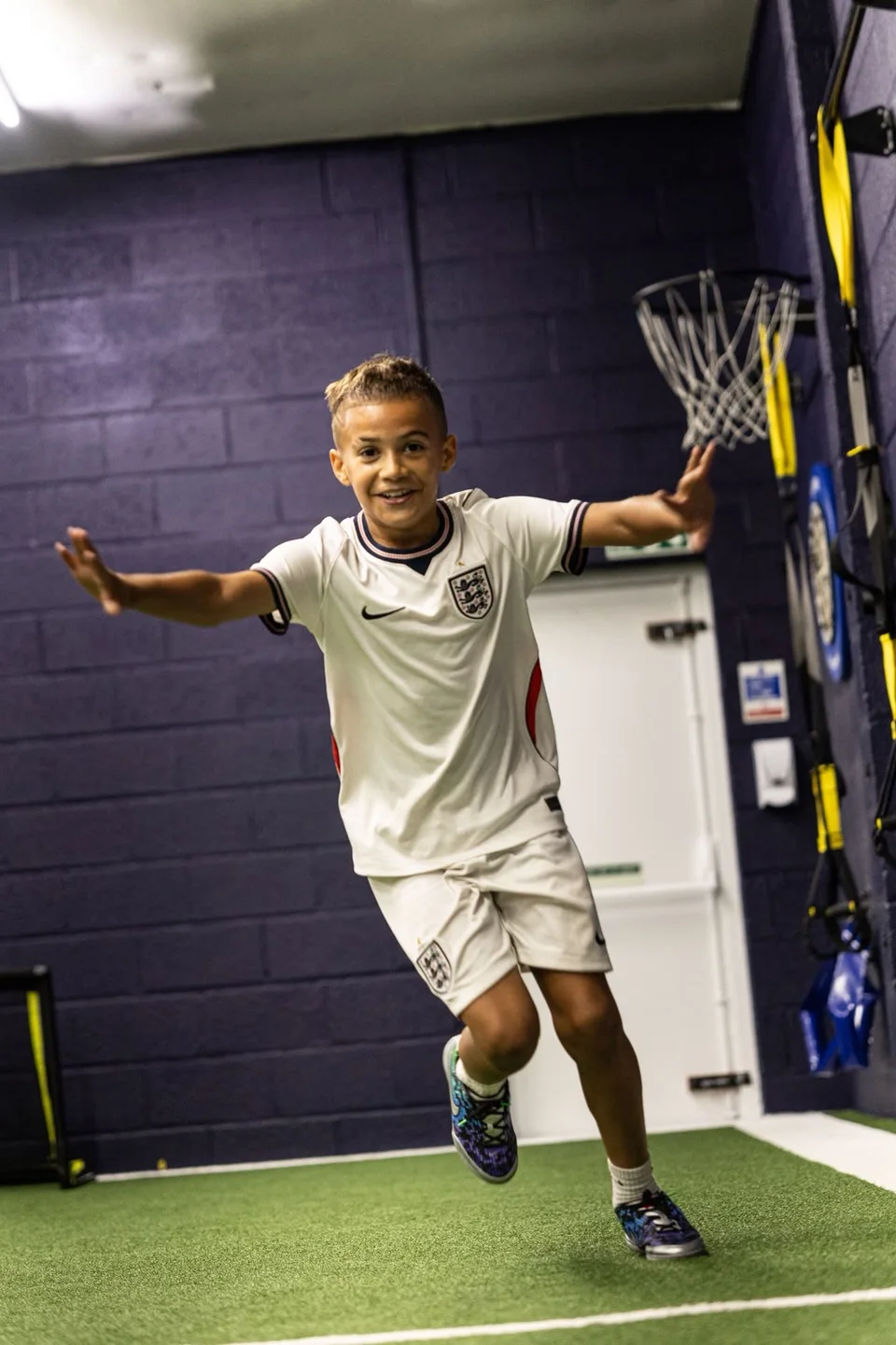 A junior athlete practising a movement drill on the indoor turf