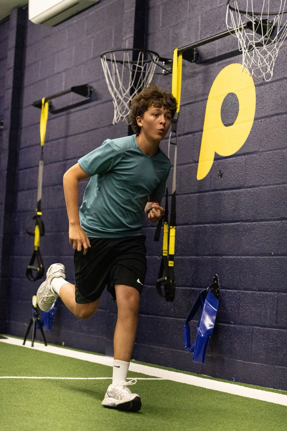 A junior athlete practising running mechanics inside Playermade
