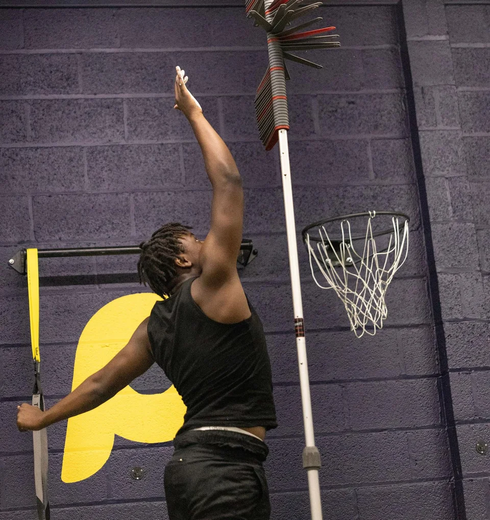 An athlete reaching for the vertical jump markers during a Movement Screen
