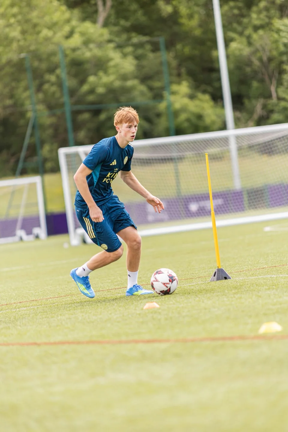 A footballer practising close control beside a training pole