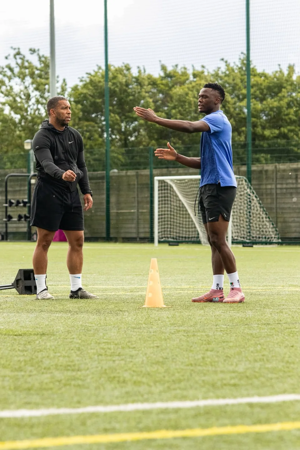 A footballer discussing a drill with a Playermade coach