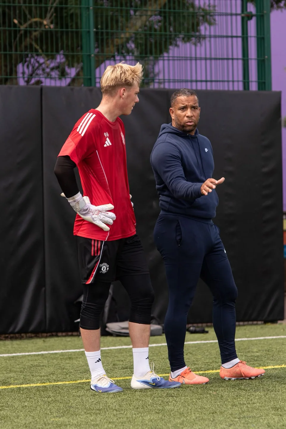 A coach explaining a drill to a goalkeeper