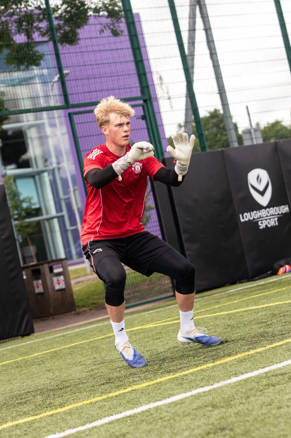 A goalkeeper practising footwork with hands raised to receive the ball