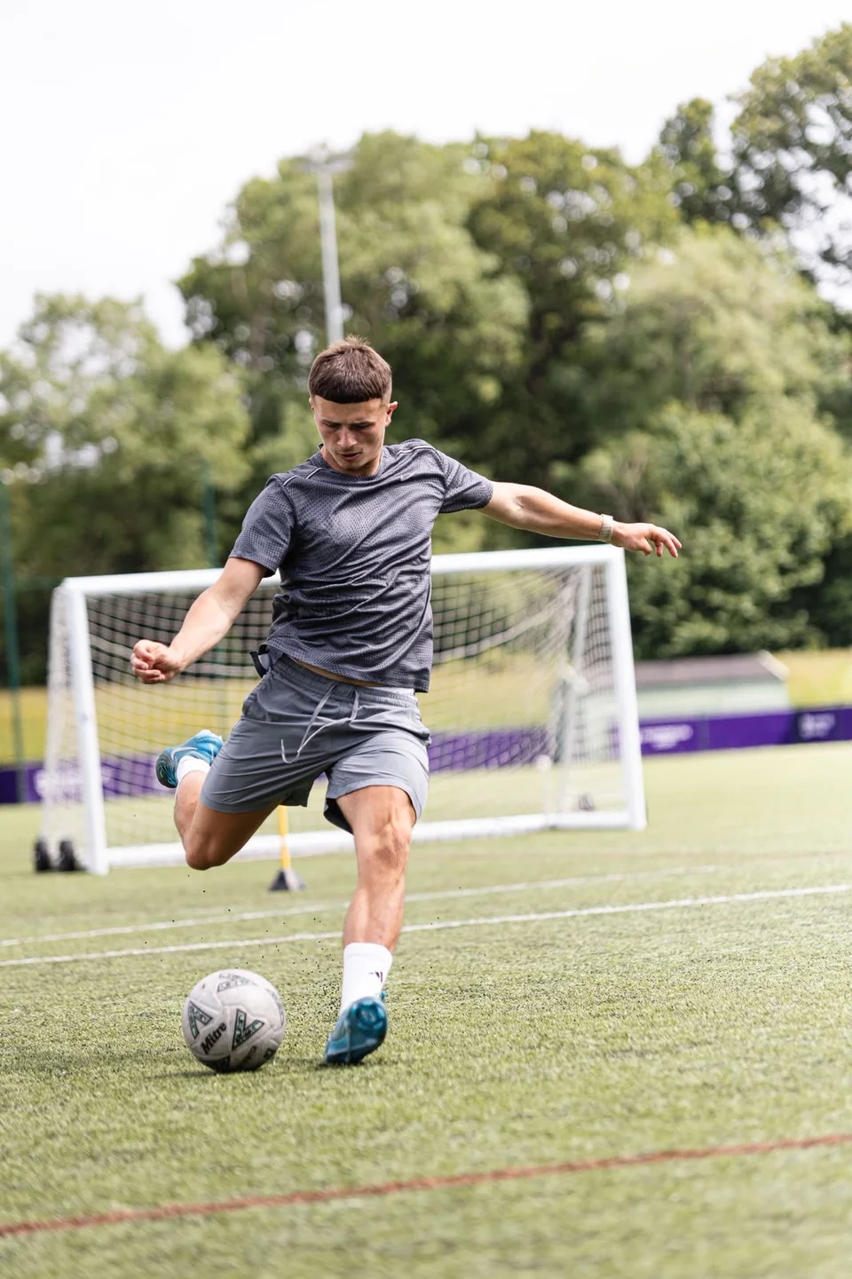 A footballer striking a ball towards goal during training