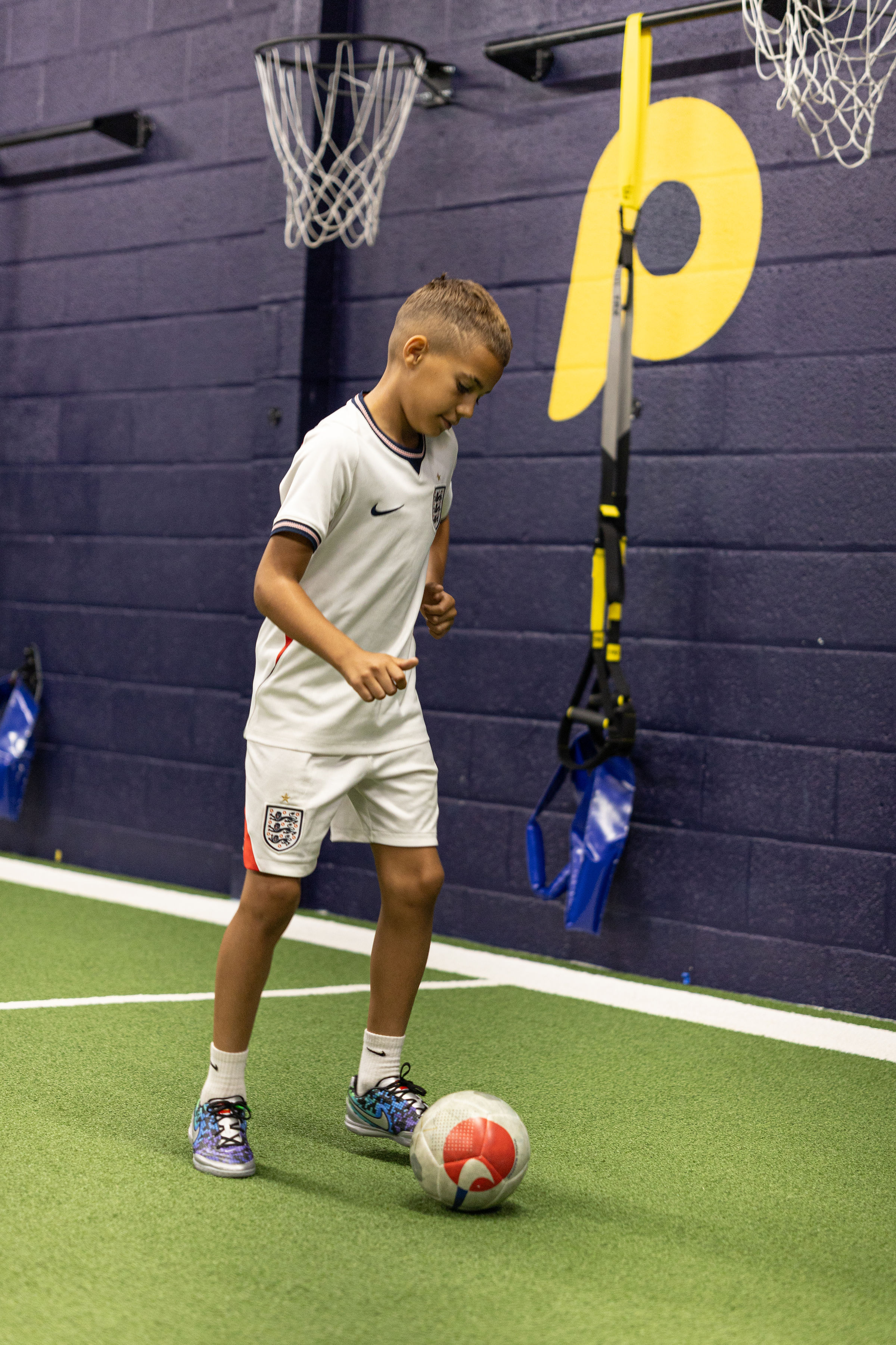 A young footballer controlling a ball on the indoor training turf