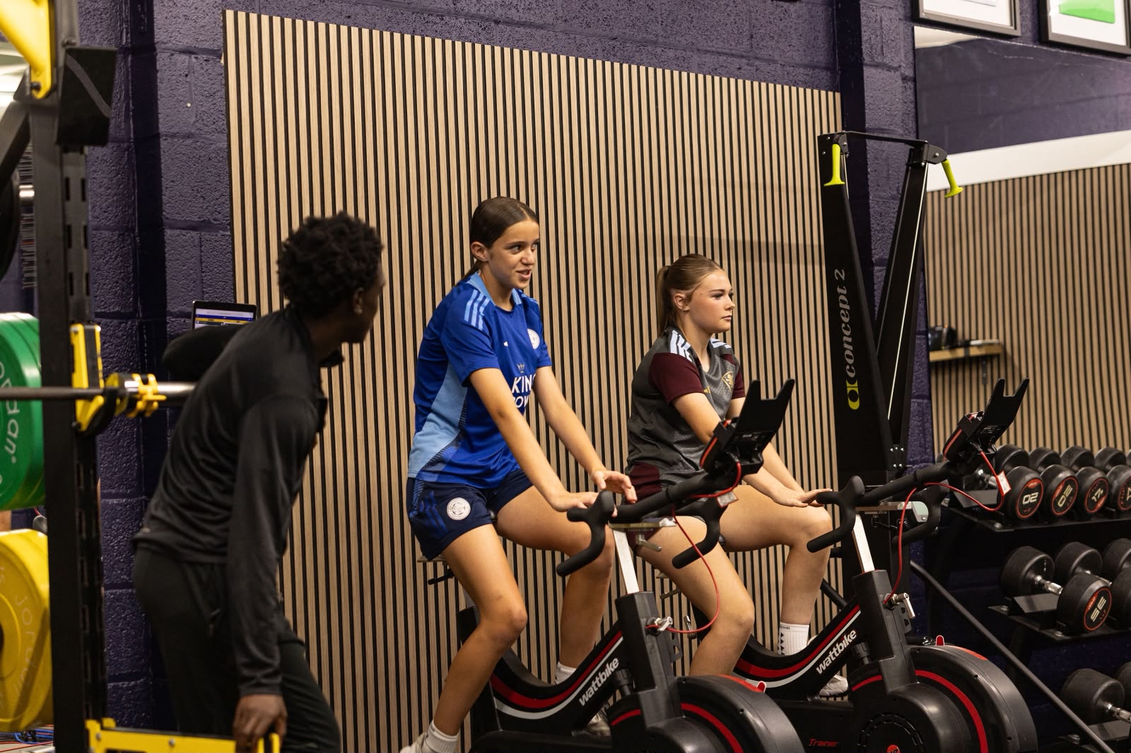 Two athletes using Wattbikes with a coach alongside them