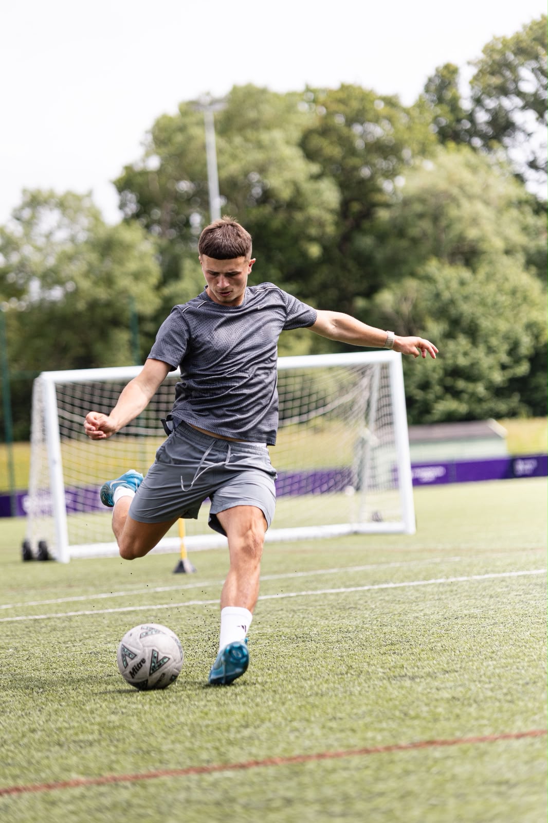 A footballer striking a ball towards goal during training
